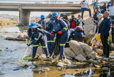 A group of people removes trash from a river.