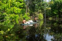 Two men paddle a canoe in the Amazon rainforest. 
