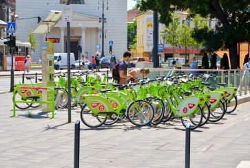 Two people checking out bicycles from a bike-share rack.
