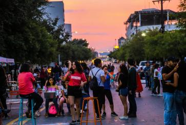 People gather in the middle of a Monterrey street during sunset