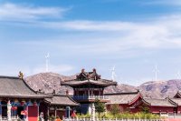 Roofs of temples in China with wind turbines in distance.