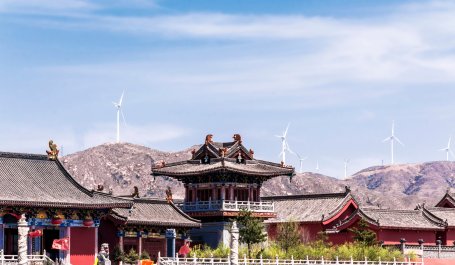 Roofs of temples in China with wind turbines in distance.