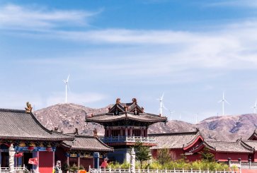 Roofs of temples in China with wind turbines in distance.