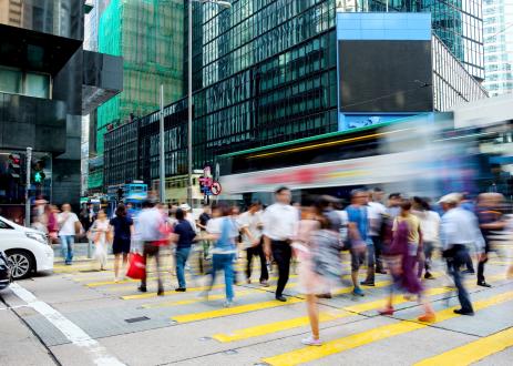 Busy city street with pedestrians and buses in the background.