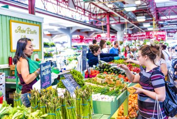 A woman buys vegetables at a market