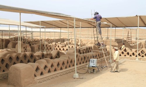 A worker on a ladder helping to restore the Chan Chan Archaeological Zone.