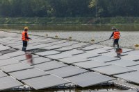 Workers clean floating solar panels.