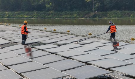 Workers clean floating solar panels.