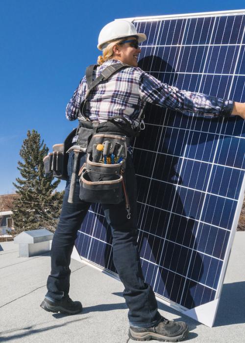 Women holding solar panel on roof