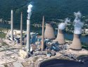 Aerial view of smoke coming from a coal-fired power plant on the banks of a river.