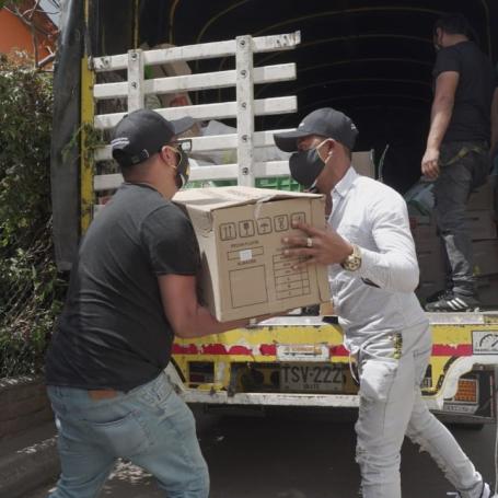 Two men load cardboard boxes of donated food onto a truck.