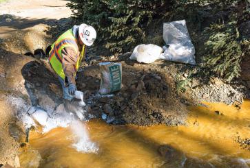 An EPA worker sprinkles lime powder in a polluted river.