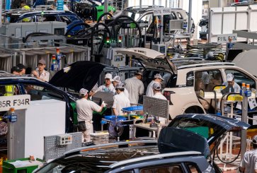 Workers assemble electric cars in a factory