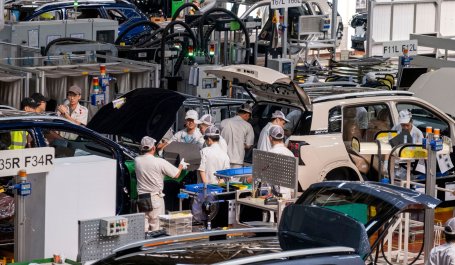 Workers assemble electric cars in a factory