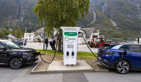 Two electric cars plugged in at a charging station. 