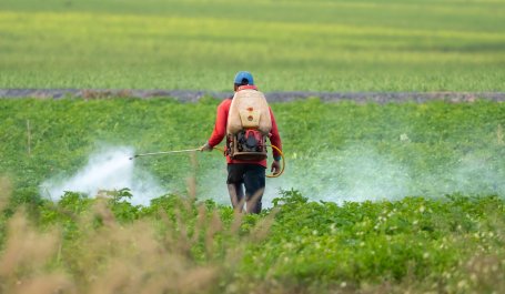 A farmer spraying pesticide on a field.