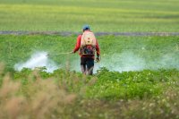 A farmer spraying pesticide on a field.