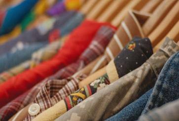 A close-up of multiple different colored button-ups on hangers. 