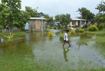 A young girl wades through a flooded village after a tropical cyclone hit Fiji in 2016. Flood events and storm surges have become increasingly common in the country in recent years. 