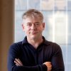 Portrait photograph of Greg Jackson standing with folded arms