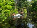 Two men paddling a boat to collect acai berries in the Amazon Rainforest.