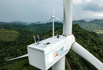 Two technicians working on top of a large wind turbine.