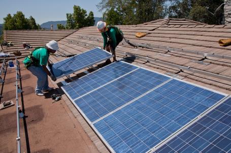 Two men install rooftop solar panels