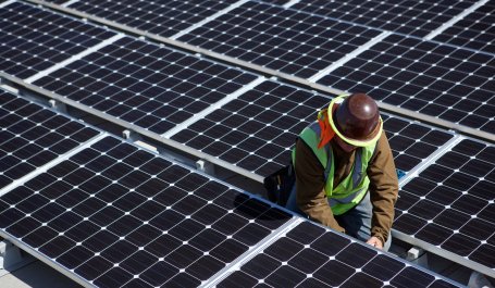 Technician installing solar panels on roof.