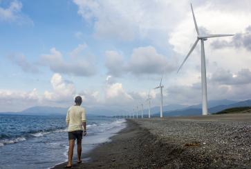 Person walking on beach next to windmills