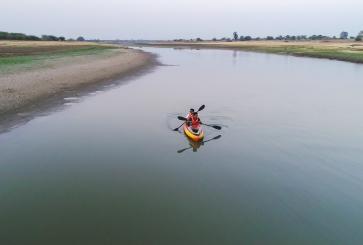 Two people in a kayak paddle down the Kham River in India.