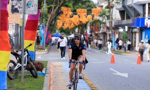 A  person wearing sunglasses and a hat rides a bicycle in a dedicated bike lane in Loja.