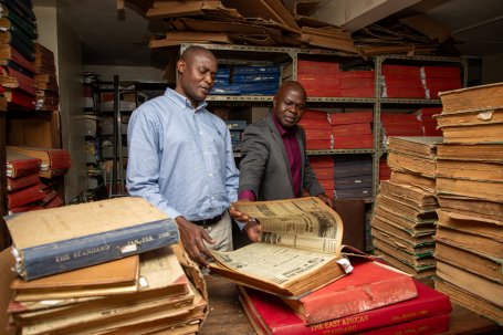 Two men look through old newspaper archives.