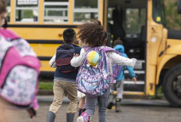 Multi-ethnic group of elementary age children getting on a school bus