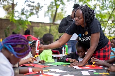 A teacher helps students during an outdoor art class.