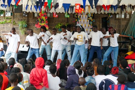 Students performing a dance under holiday decorations in front of an audience.