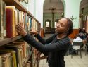 A woman looks through books on a shelf.