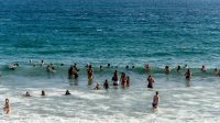 People stand and swim in the ocean.