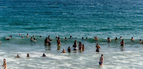 People stand and swim in the ocean.