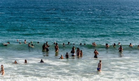 People stand and swim in the ocean.