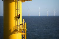 A worker climbing the ladder on the side of a floating wind turbine. 