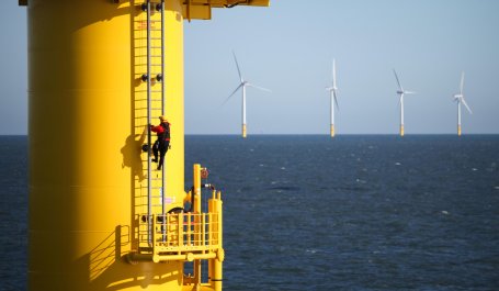 A worker climbing the ladder on the side of a floating wind turbine. 