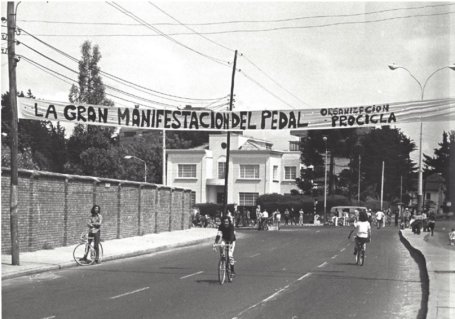 A black and white image of people walking and riding bicycles on a street.