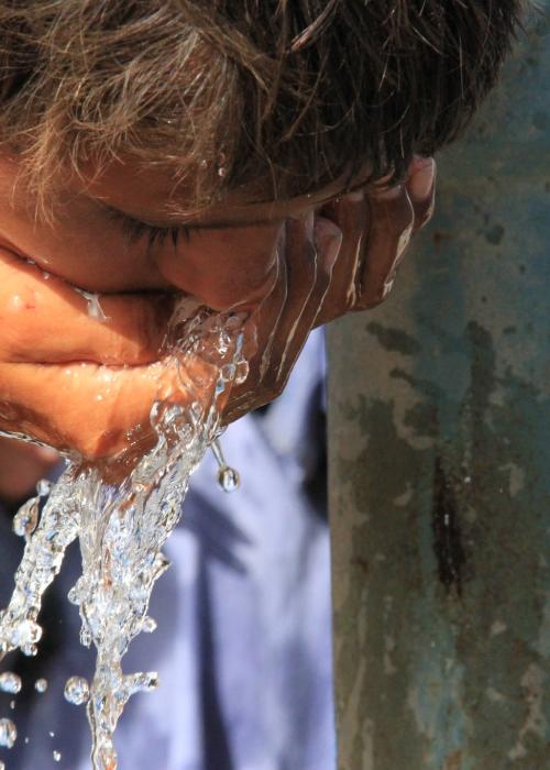 Person drinking water from water spout.