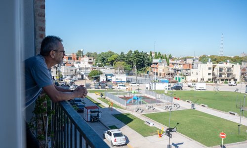 A man on his apartment balcony overlooks a new playground in his neighborhood.