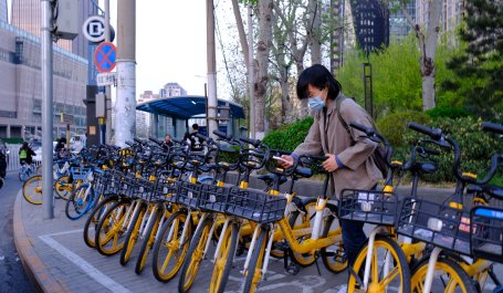 A person removes a bicycle from a lineup of shared bicycles.