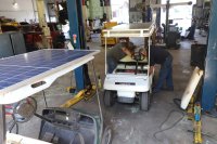 An instructor and student in an automotive garage working on a solar-powered golf cart.