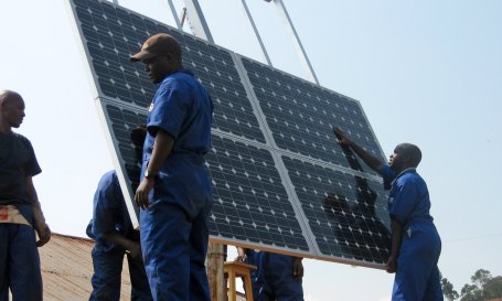Workers installing solar panels on a hospital roof.