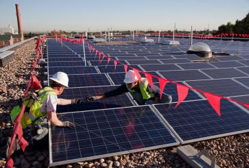 Workers installing solar panels at elementary school.