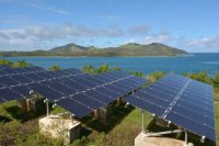 Solar panels near the ocean with islands in the background. 