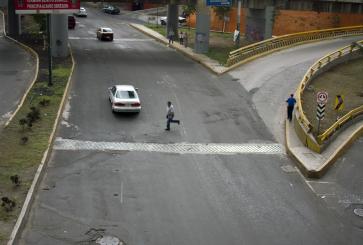 A person runs across a wide street.
